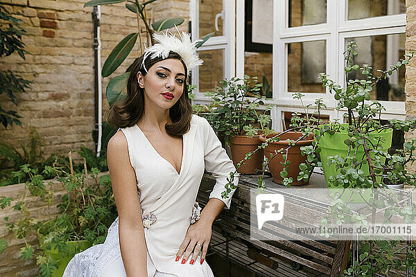 Schöne Braut sitzt im Garten bei Pflanzen