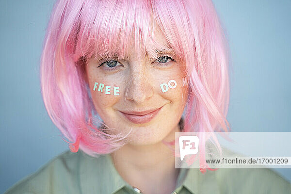 Junge Frau mit rosa Perücke  Buchstaben im Gesicht  Freiheit