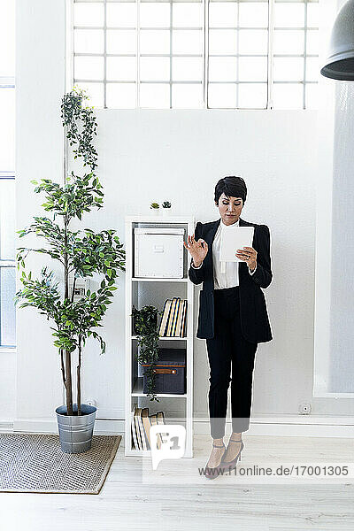 Geschäftsfrau stehend im Büro mit Dokumenten in der Hand