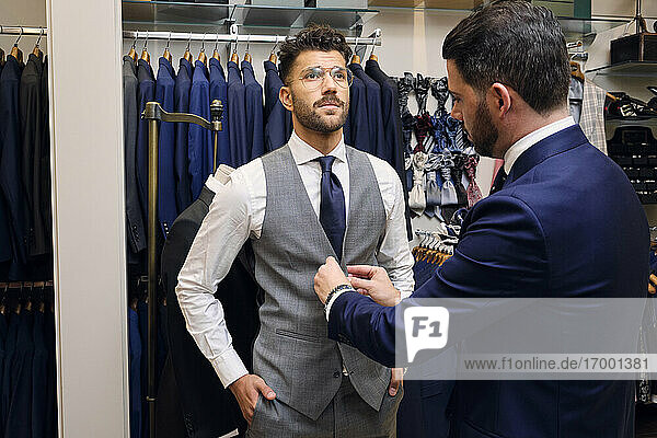 Tailor in his menswear store buttoning customers waistcoat