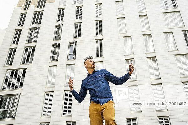 Mann tanzt gegen weißes Gebäude