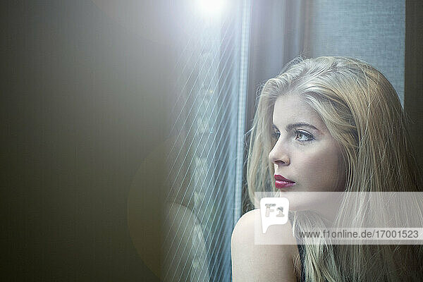 Schöne blonde Frau schaut durch das Fenster