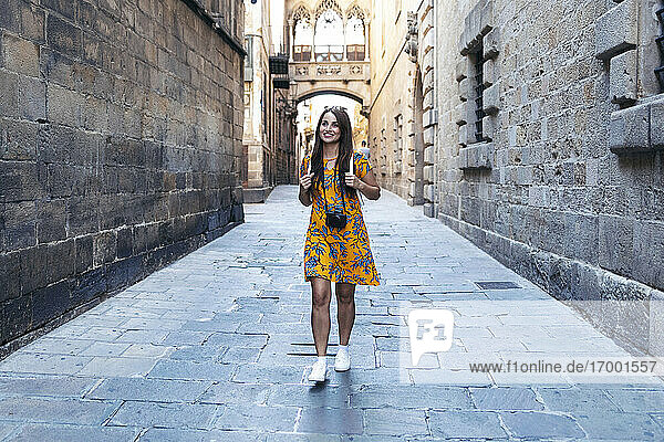 Mittlere erwachsene Frau lächelt beim Gehen auf dem Fußweg im Gotischen Viertel  Barcelona  Katalonien  Spanien