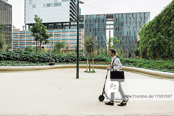 Businessman with electric push scooter in city
