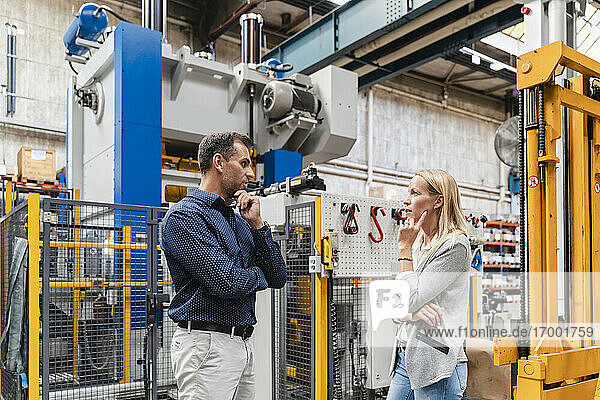 Thoughtful businessman and female colleague discussing in factory