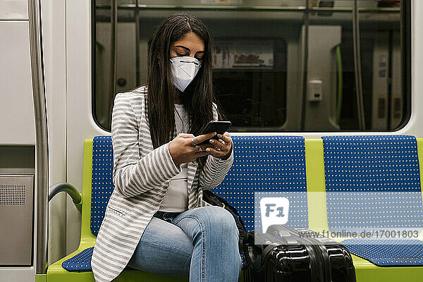 Weiblicher Fahrgast  der im U-Bahn-Zug sitzend sein Smartphone benutzt