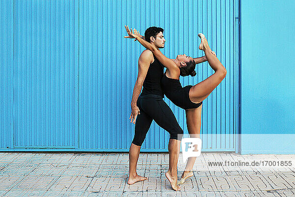 Männliche und weibliche professionelle Turner üben Akrobaten an einer blauen Metallwand