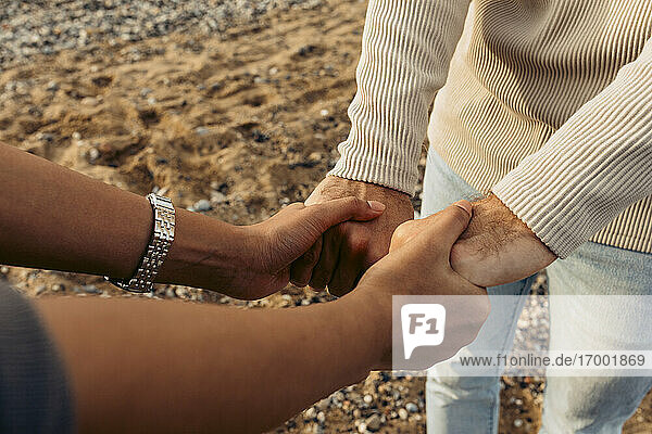 Junges Paar hält Hände am Strand
