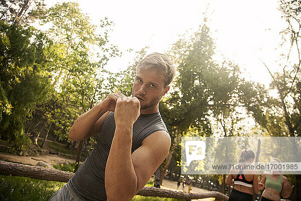 Sportsman practicing shadow boxing while standing with friends in background outdoors