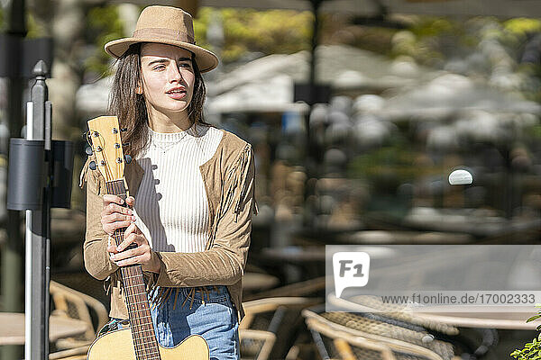 Nachdenkliche junge Frau mit Gitarre an einem sonnigen Tag