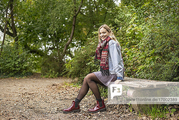 Attractive woman sitting on bench in autumnal park