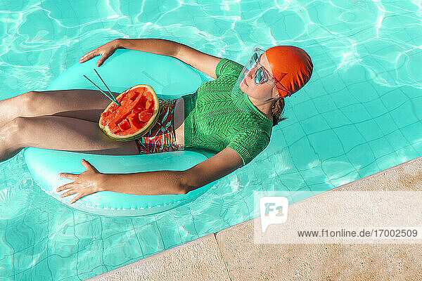 Frau mit Schwimmreifen und Wassermelone im Schwimmbad