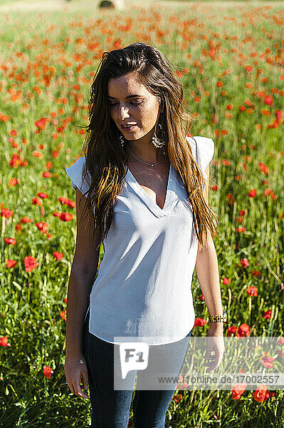 Beautiful woman standing at poppy field during springtime