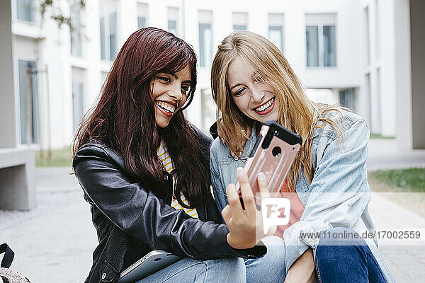 Cheerful young female university students taking selfie at campus