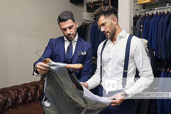 Tailor and customer looking at gray waistcoat in tailors boutique