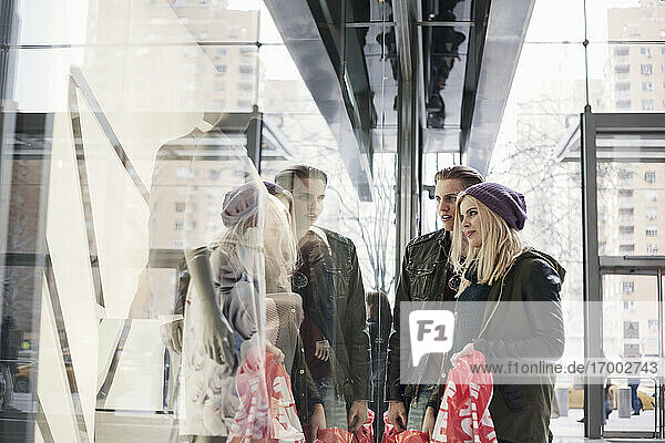 Young woman doing window shopping while standing with man by store window