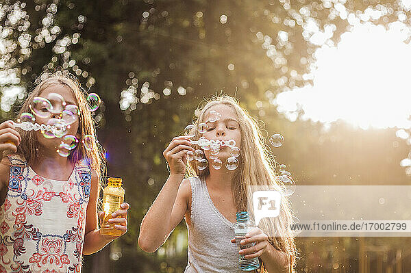 Mädchen blasen Seifenblasen im Park bei Sonnenuntergang