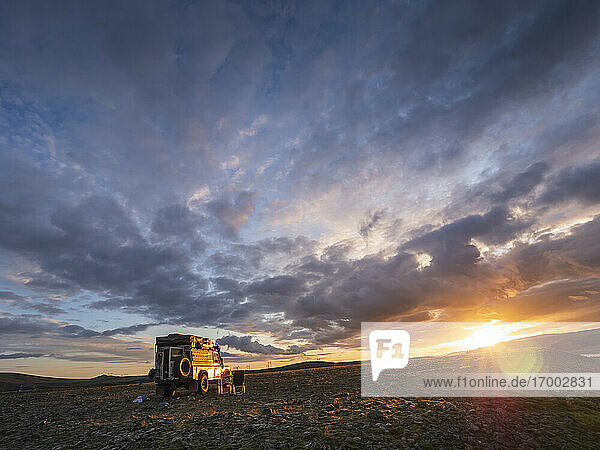Cloudy sky over off-road car parked in remote Icelandic location at sunset