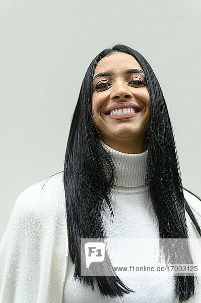 Lächelnd schöne junge weibliche Fachkraft mit langen schwarzen Haaren vor weißem Hintergrund