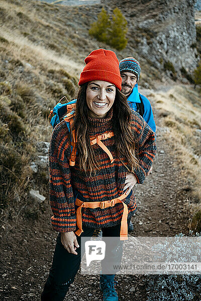 Smiling woman hiking with boyfriend on rocky mountain during vacation