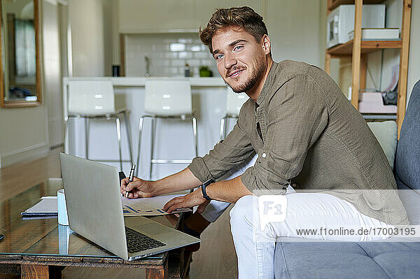 Smiling businessman sitting with documents at home