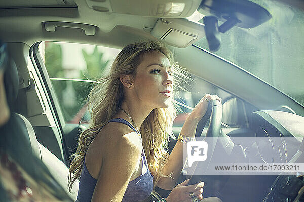Blonde Frau  die während einer Autofahrt mit einem Freund nach draußen schaut