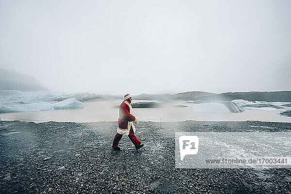 Island  Weihnachtsmann geht in Gletscherlandschaft