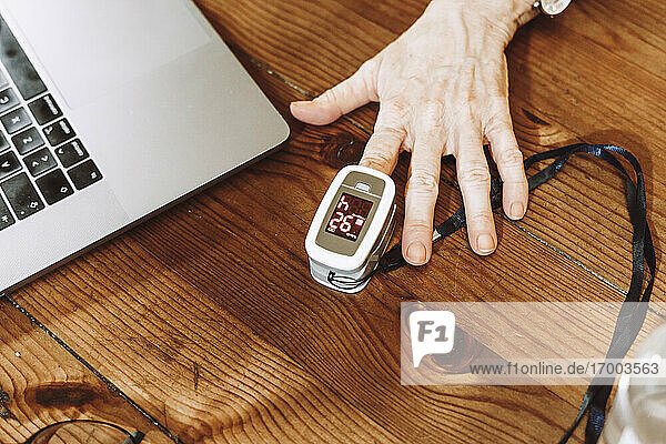 Ältere Frau prüft den Puls mit einem Oximeter zu Hause