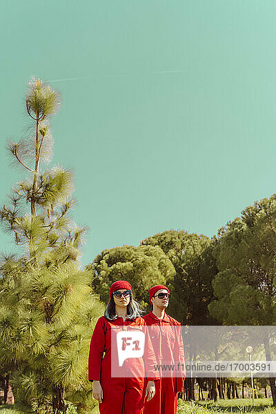 Young couple wearing red overalls and hats standing in nature