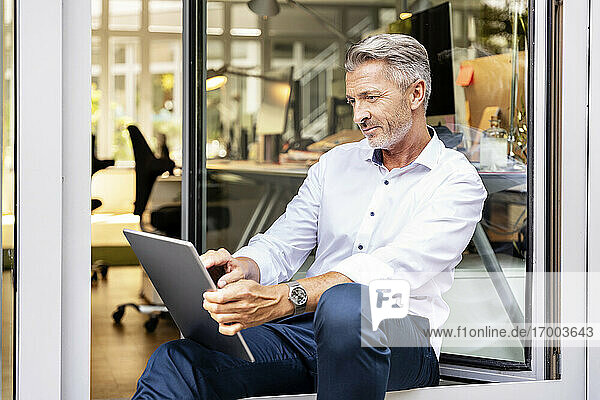 Businessman working on digital tablet while sitting in office