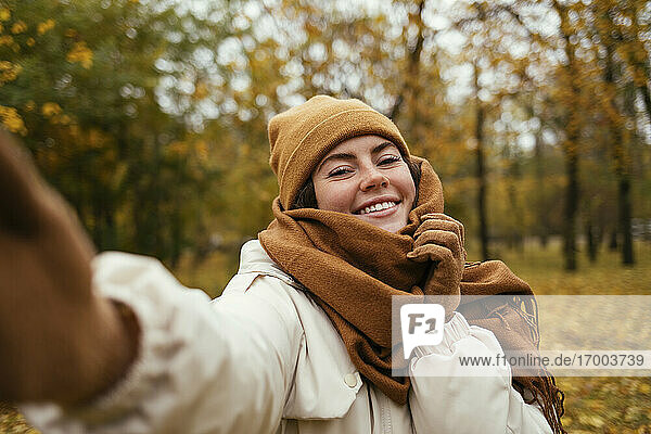 Happy young woman taking selfie in autumn park