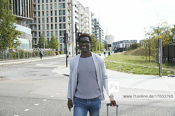 Smiling businessman walking on street in city