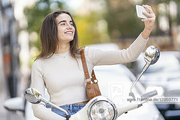Frau mit Motorroller nimmt Selfie auf Smartphone