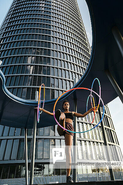 Sportliche Frau  die mit Plastikreifen vor einem modernen Bürogebäude trainiert