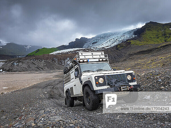 Mann fährt Geländewagen gegen den bewölkten Himmel am Svinafellsjokull  Island