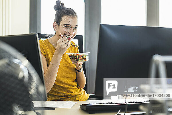 Junge Geschäftsfrau beim Essen in der Mittagspause im Büro