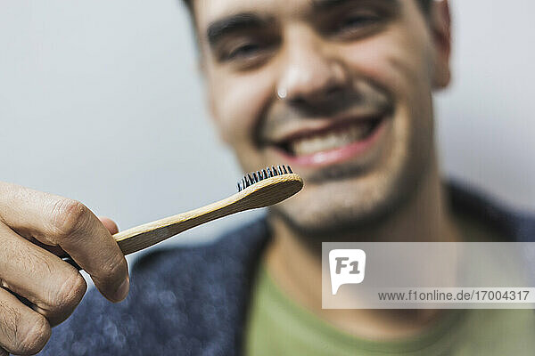 Lächelnder Mann beim Zähneputzen mit Bambuszahnbürste