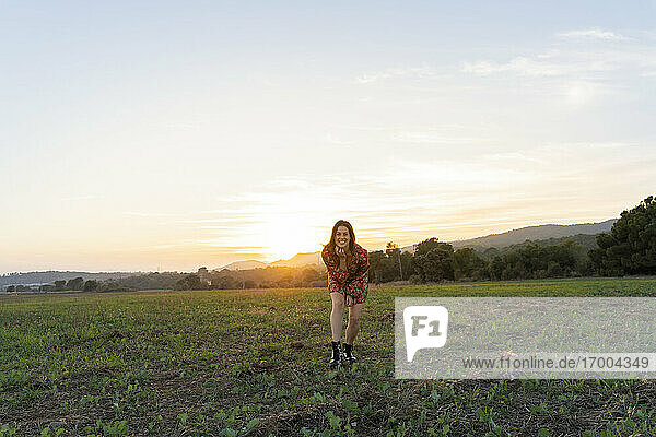 Junge Frau genießt den Sonnenuntergang auf dem Lande gegen den Himmel