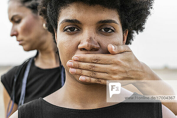 Woman's hand covering mouth of another woman  close-up