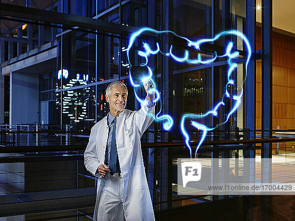 Lächelnder männlicher Gastroenterologe bei der Untersuchung des Dickdarms mit Lichtmalerei im Krankenhaus
