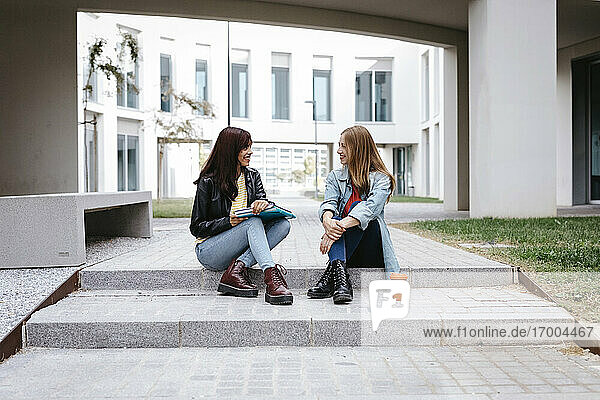 Young female university students sitting on steps at campus