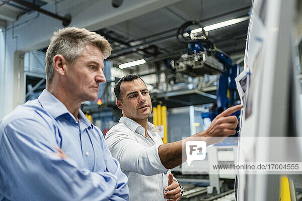 Ein männlicher Unternehmer erklärt seinem Vorgesetzten während einer Besprechung in einer Fabrik die Geschäftsstrategie