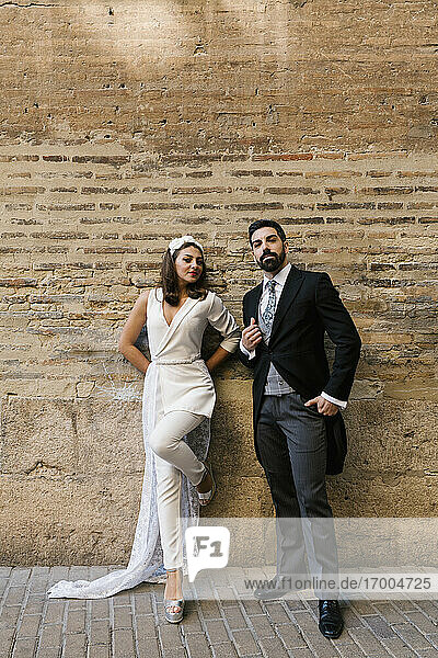 Junges  frisch verheiratetes Paar  das auf dem Gehweg an der Wand steht
