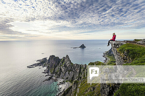 Explorer admiring view while sitting on Matind mountain at Andoya  Norway
