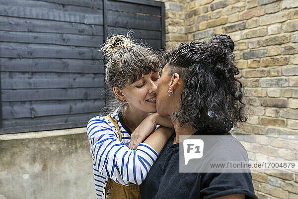 Lesbian couple kissing while standing at back yard