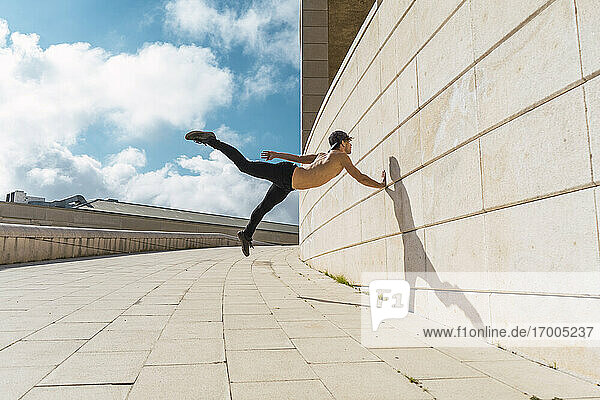 Junger Mann macht Akrobatik an einer Wand im Freien