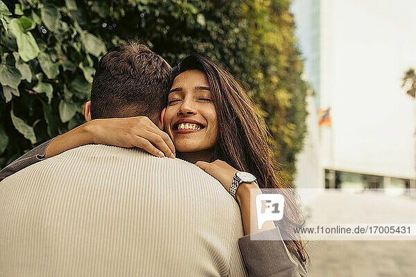 Smiling girlfriend embracing boyfriend at park