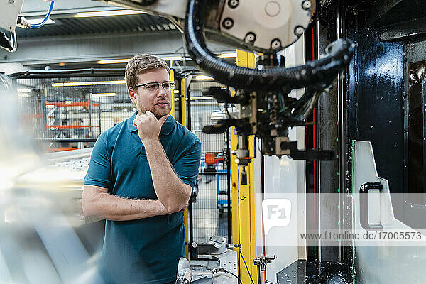 Thoughtful male worker examining while standing at factory