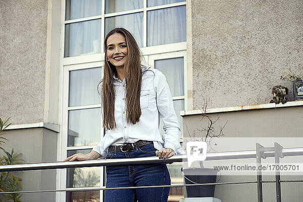 Junge Geschäftsfrau lächelt  während sie auf einem Balkon steht