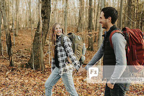 Junges Paar hält sich bei einer Herbstwanderung an den Händen